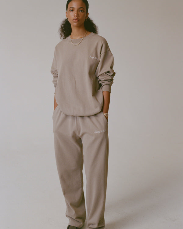 Person wearing a beige sweatshirt and pants set against a plain background