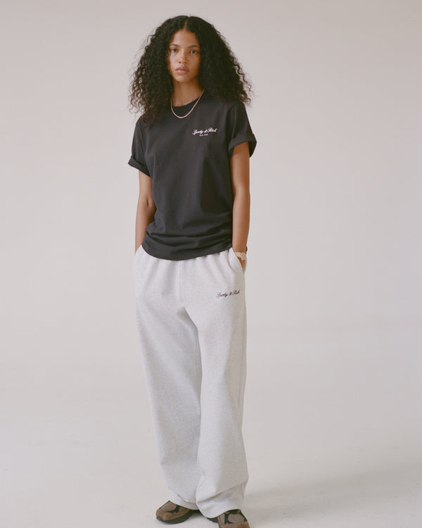 Person wearing a black t-shirt and gray sweatpants on a plain background