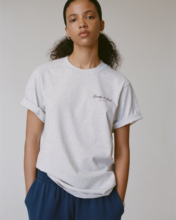 Person wearing a gray t-shirt with text on a plain background