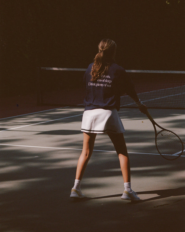 Person playing tennis on a court with a dark background