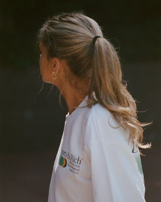 Person wearing a white jacket with a brand logo on a dark background