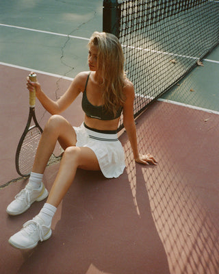 Woman sitting on a tennis court holding a racket