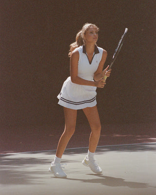 Woman playing tennis on a court with a dark background