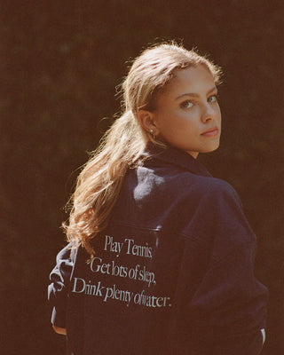 Person wearing a jacket with motivational text on the back against a dark background