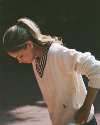 Woman wearing a cream-colored sweater with a dark collar and trim.