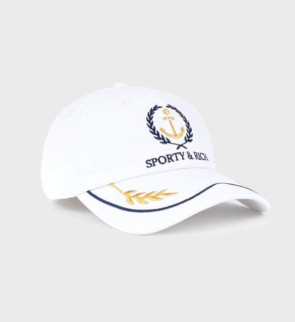 The Yacht Hat in White/Metallic Gold/Dark Navy features anchor and laurel embroidery, Sporty & Rich text, a gold leaf brim accent, and an adjustable closure for a perfect fit.