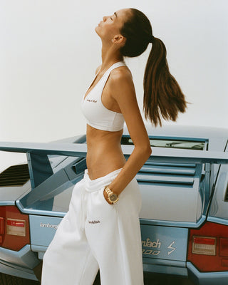 Woman in white outfit standing in front of a vintage car