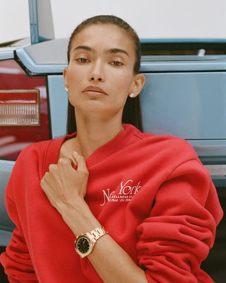 Person wearing a red sweatshirt with 'New York' text, standing in front of a vintage vehicle.