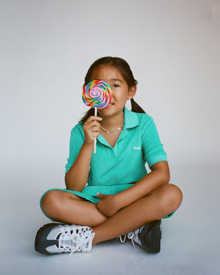 Child holding a colorful lollipop against a plain background