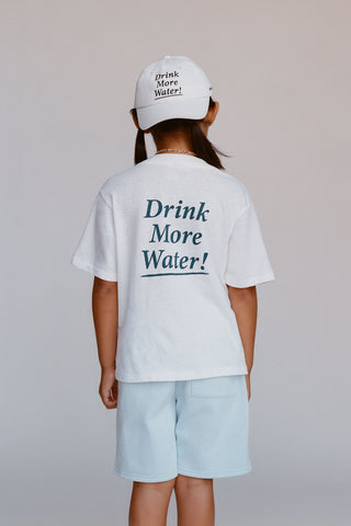 kids wearing a white t-shirt with 'Drink More Water!' text, paired with a white cap on a plain background