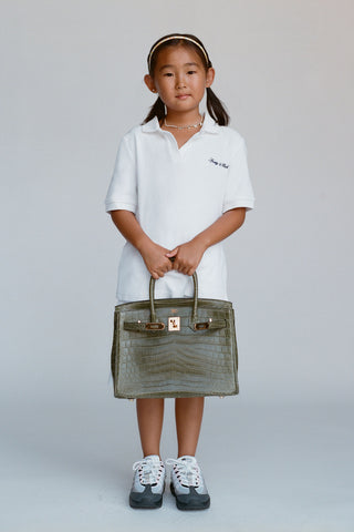 Child holding a green handbag against a plain background