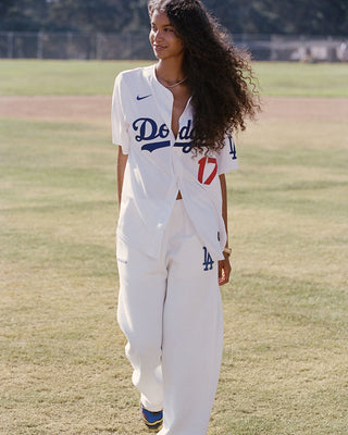 LA Serif Wide Sweatpant - White/Team Blue, crafted in Portugal from 100% cotton, features a wide-leg silhouette with blue LA and Sports Rich logos and is displayed on a plain light gray background.