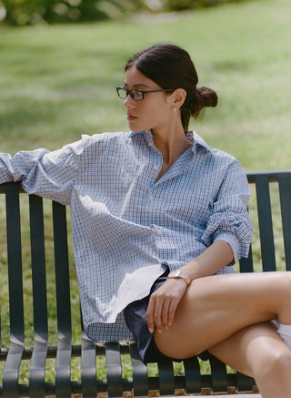 Coco SRC Oversized Shirt - Blue Mini Check features a blue and white mini check pattern in a long-sleeve, button-up, oversized silhouette with a collar. Crafted from breathable poplin for a relaxed fit, the shirt is displayed laid flat on a white background.