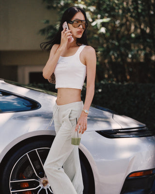 Woman talking on a phone in front of a white car
