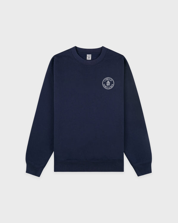 Cadillac x Sporty & Rich Payton Sweatshirt in navy blue, featuring a small white circular logo on the left chest, displayed on a white background.