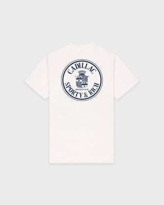 Ecru Cadillac x Sporty & Rich Atlas Tee with a small circular blue and black logo on the left chest, laid flat on a white background. Made from premium USA grown cotton, this tee offers timeless style and exceptional comfort.