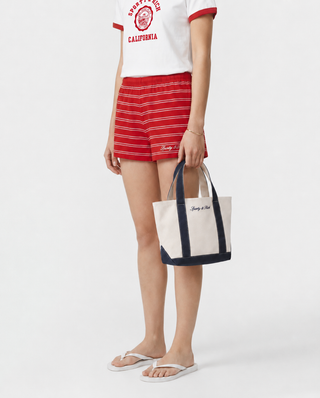 Beige tote bag with navy handles and trim on a white background
