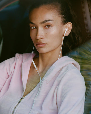 Signature Logo Krystal Zip Hoodie - Laffy/Crystal: a light pink velour zip-up hoodie with front pockets, a hood, and a cropped fit. Features a subtle crystal logo detail and is displayed on a plain white background.