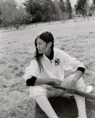 Person sitting on grass wearing a New York Yankees jacket