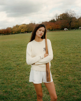 Woman holding a baseball bat in a park with trees and grass in the background