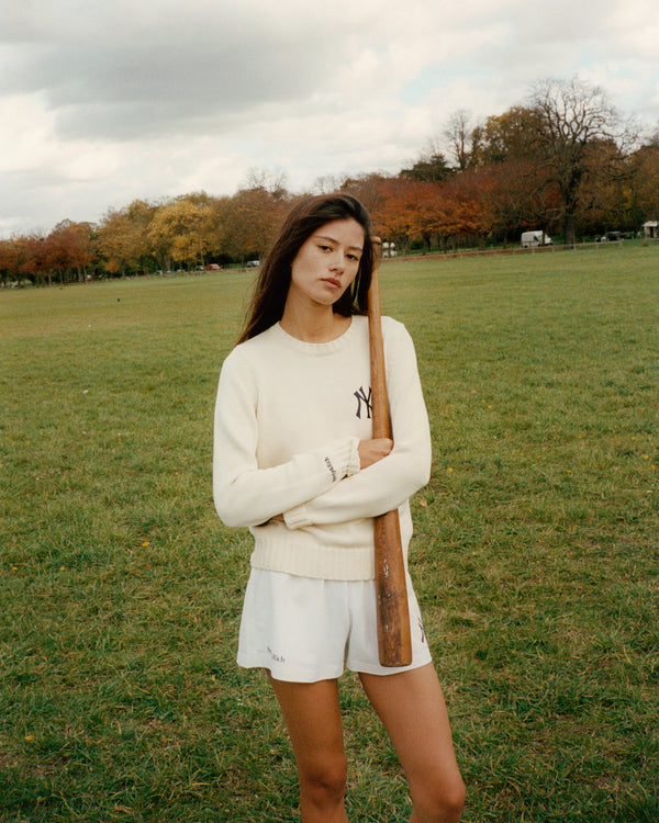 Woman holding a baseball bat in a park with trees and grass in the background