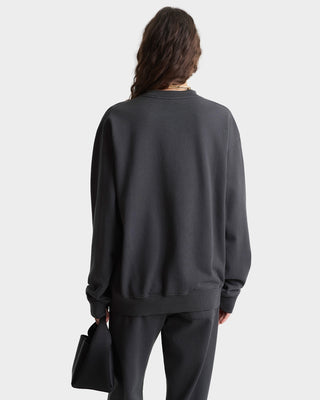 Person wearing a dark gray sweatshirt and pants on a white background