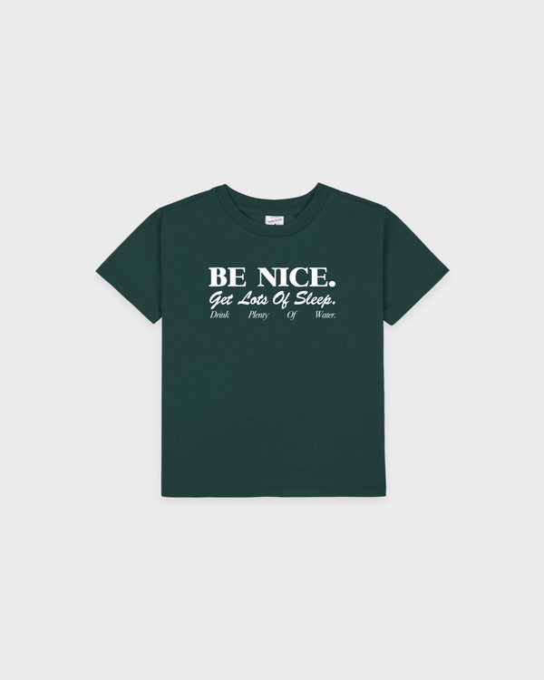Introducing the Be Nice Kids T-Shirt - Forest/White: This dark green tee features bold white text—BE NICE. Get Lots Of Sleep. Drink Plenty Of Water.—and is crafted from recycled cotton for eco-friendly comfort. Designed with an oversized fit, it’s the perfect essential for stylish, all-day wear.