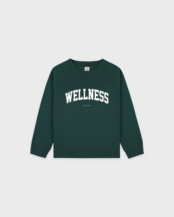 Wellness Ivy Kids Crewneck in Forest/White, an oversized-fit sweatshirt for kids crafted from a dark green cotton-polyester blend, features "WELLNESS" in bold white letters across the chest. Expertly made in Portugal and displayed laid flat on a white background.