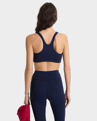 Person wearing a navy blue sports bra and leggings set on a white background