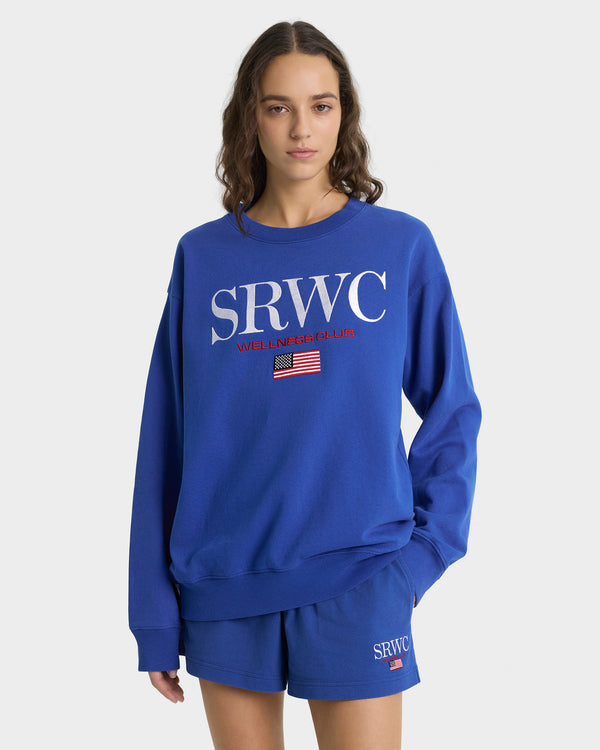 Person wearing a blue 'SRWC' sweatshirt and shorts on a white background