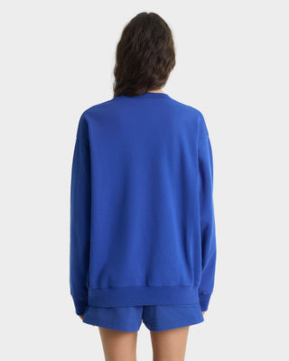 Person wearing a blue sweatshirt and shorts set on a white background