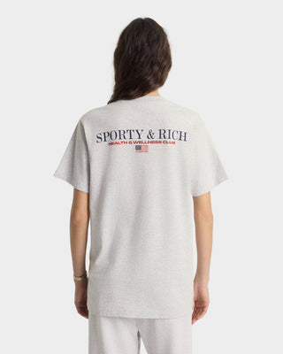 Person wearing a light gray t-shirt with 'Sporty & Rich' branding on the back, standing against a white background.
