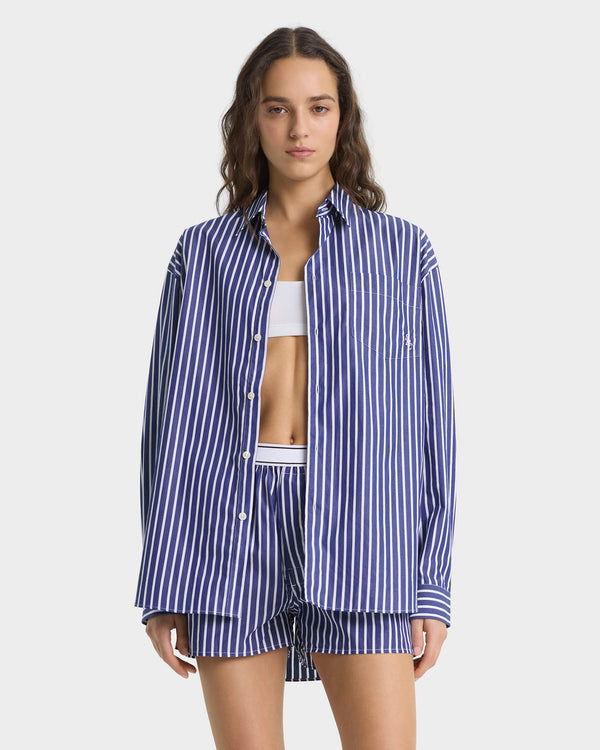 Woman wearing a blue and white striped pajama set on a white background