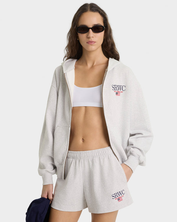 Woman wearing a gray hoodie and shorts with 'SRWC' branding on a white background