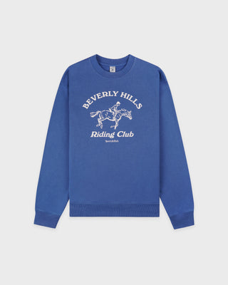 Blue sweatshirt with 'Beverly Hills Riding Club' text and graphic on a light gray background