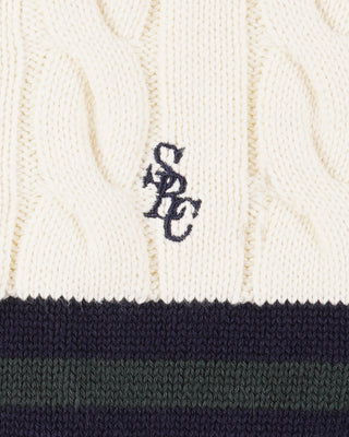 Close-up of a cable knit sweater with a logo on a white background