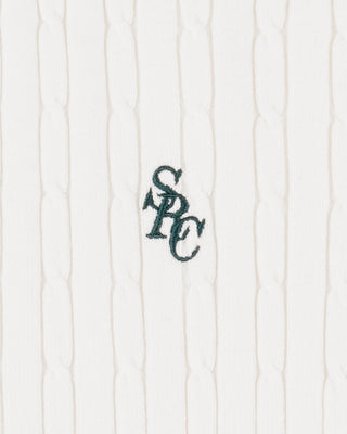 Textured white fabric with a dark green embroidered logo on a white background