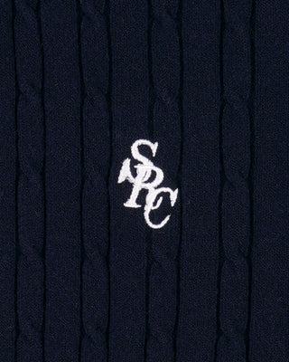 Close-up of a navy blue textured fabric with a white logo on a dark background