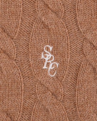 Close-up of a brown knitted fabric with a white logo on a brown background