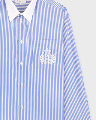Blue and white striped shirt with a logo on the chest against a light gray background