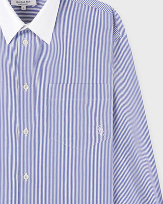 Blue and white striped shirt with a brand label on a light gray background