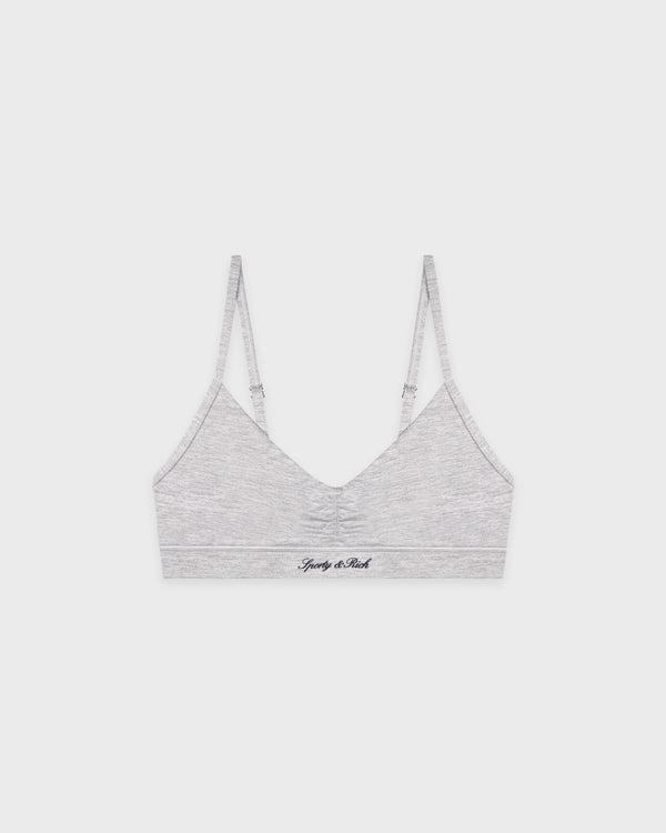 Woman wearing a gray sports bra and leggings set on a white background