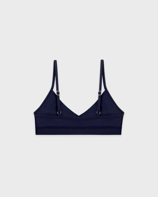 Navy blue bralette with thin straps on a light gray background
