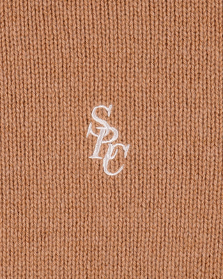 Close-up of a brown fabric with a white embroidered logo on a plain background