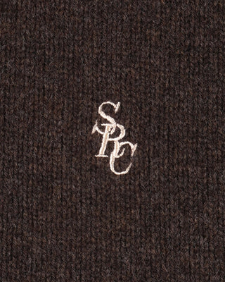 Close-up of a textured brown fabric with a white embroidered logo.