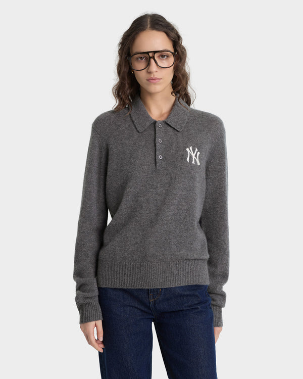 Person wearing a gray sweater with a logo on a white background