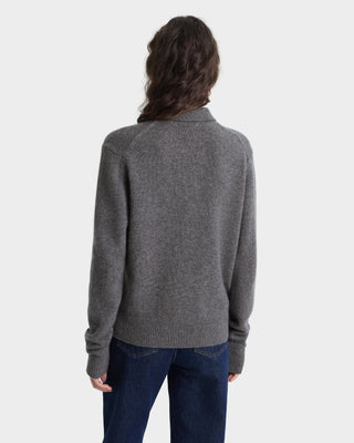 Person wearing a gray sweater and blue jeans on a white background