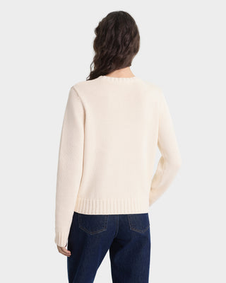 Person wearing a cream sweater and blue jeans on a white background