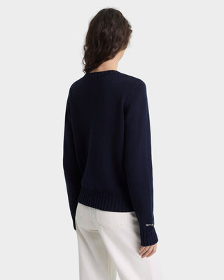 Person wearing a navy sweater with a white background
