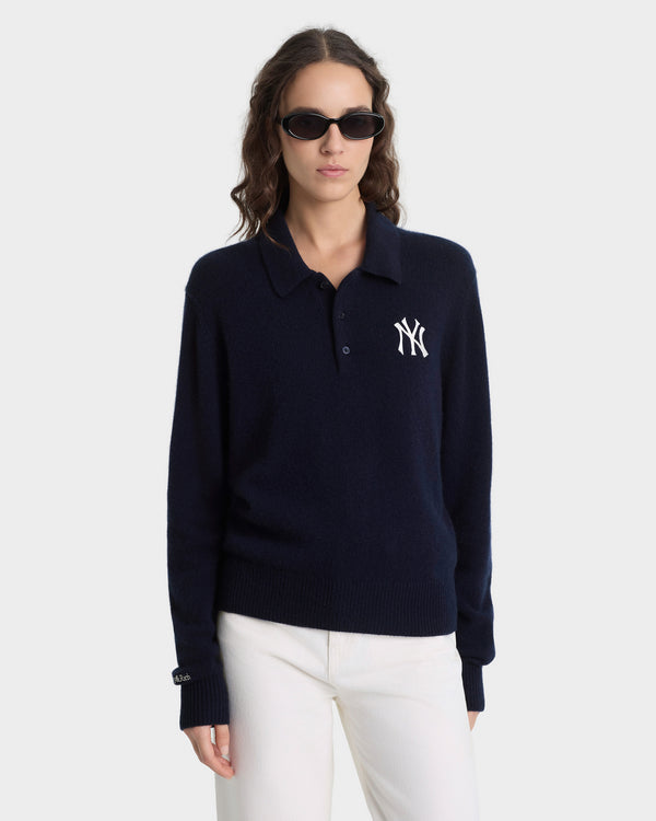 Woman wearing a navy blue polo shirt with a logo on a white background